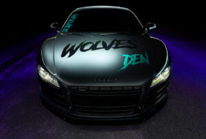 Audi R8 front view with Wolves Den logo against industrial background, lit with light painting technique by Radiant Photography.